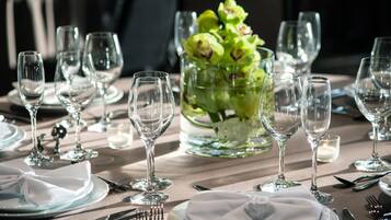 A dining table set with multiple wine glasses, plates, and cutlery, with a centerpiece of green flowers.