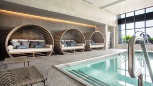 A modern indoor pool area with three circular seating areas and a pool. - The Row Hotel at Assembly Row, Autograph Collection (Somerville)