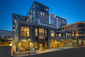 A modern hotel with multiple floors, large windows, and a well-lit entrance.