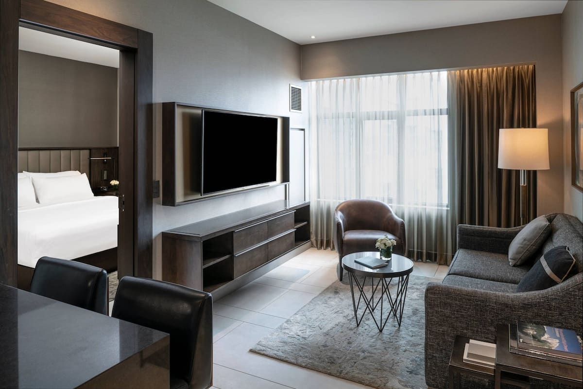 Ein modernes Hotelzimmer mit Bett, Fernseher, Sofa und Essbereich.
