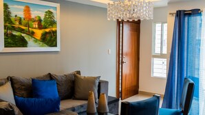 Un salon moderne avec un canapé, deux fauteuils bleus, une table basse et un lustre.