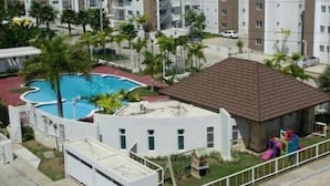 Un ensemble résidentiel comprenant plusieurs immeubles d’appartements, une piscine et un petit espace de jeux pour enfants.