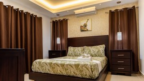 Une chambre à coucher bien aménagée, avec un grand lit, deux tables de chevet et un climatiseur fixé au mur.