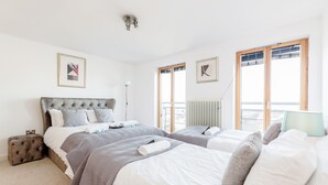 A hotel room with two beds, a large window, and a radiator. - Premium London Excel Apartment (London)