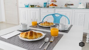 Desayuno con croissants, zumo de naranja y un mantel blanco.