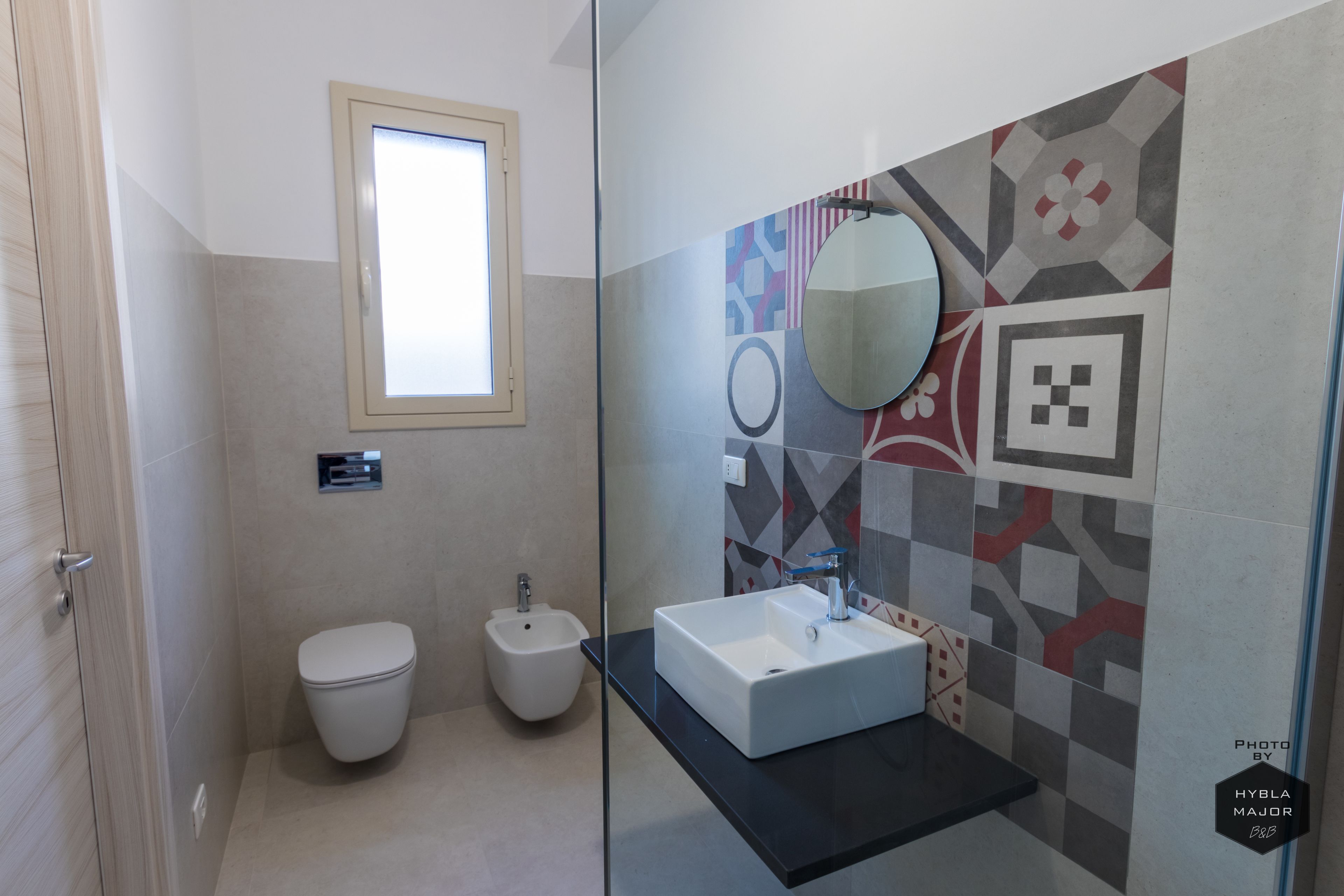 Un bagno moderno con toilette, bidet e zona lavabo vetrata.