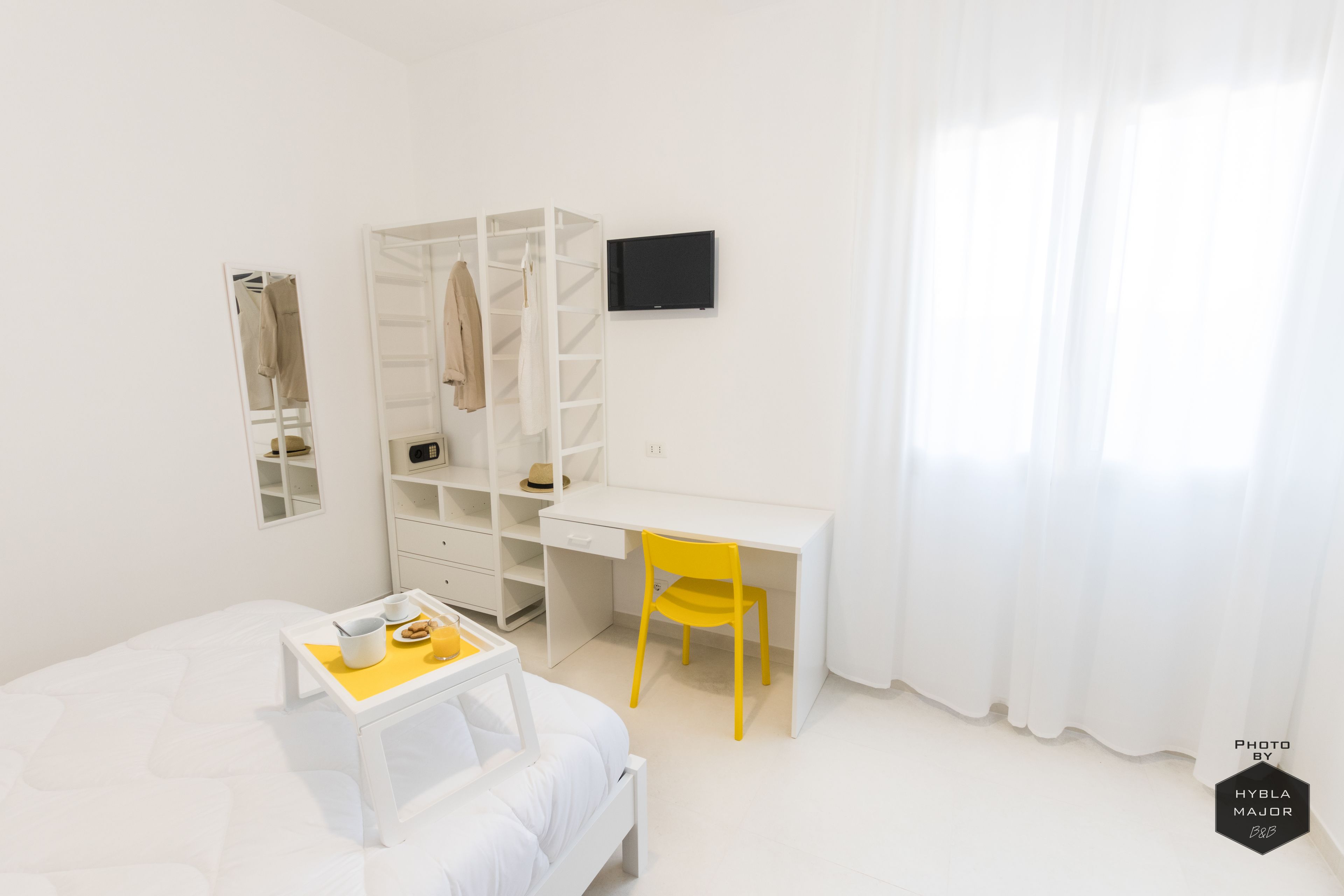 Un dormitorio con cama, escritorio, silla, armario y televisor.