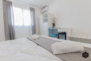 A hotel room with a bed, a desk, a chair, and a small table. - Hybla Major B&B (Avola)
