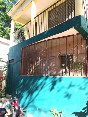 A building with a blue exterior, a barred window, and a balcony with a metal railing.