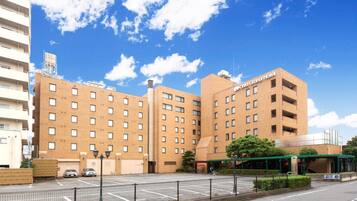 A multi-story hotel with a brick facade, a parking lot, and a clear blue sky.