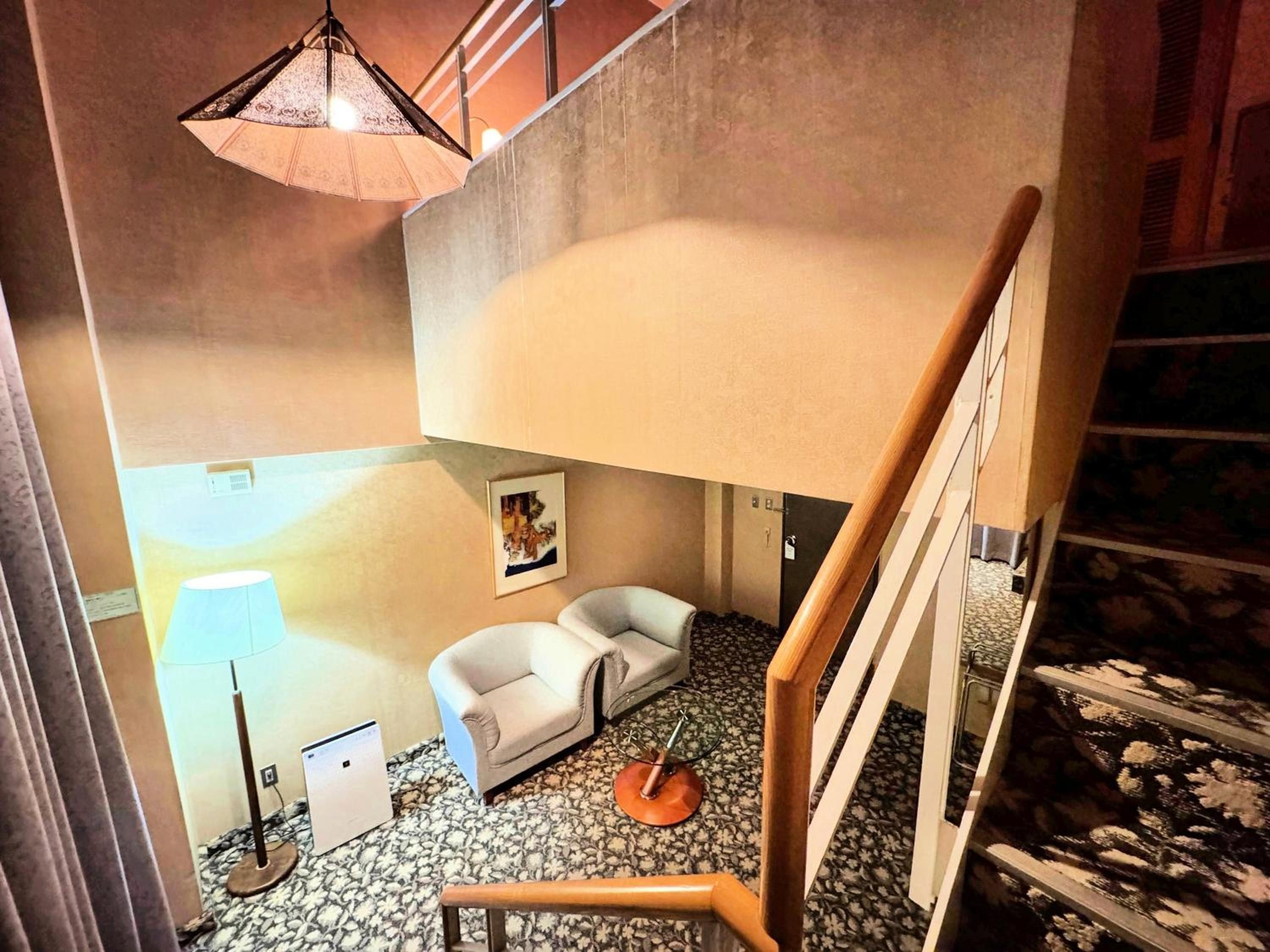 A room with a sofa, a lamp, a picture on the wall, and a staircase.