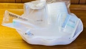 Una bolsa de plástico con un cepillo de dientes y un afeitor sobre una mesa de madera.