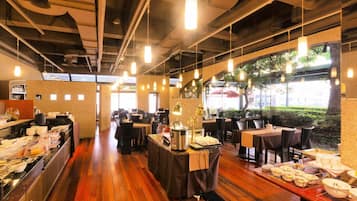 A restaurant with wooden flooring, tables set for dining, and hanging pendant lights.