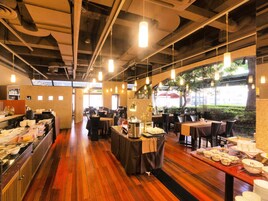 A restaurant with wooden flooring, tables set for dining, and hanging pendant lights.