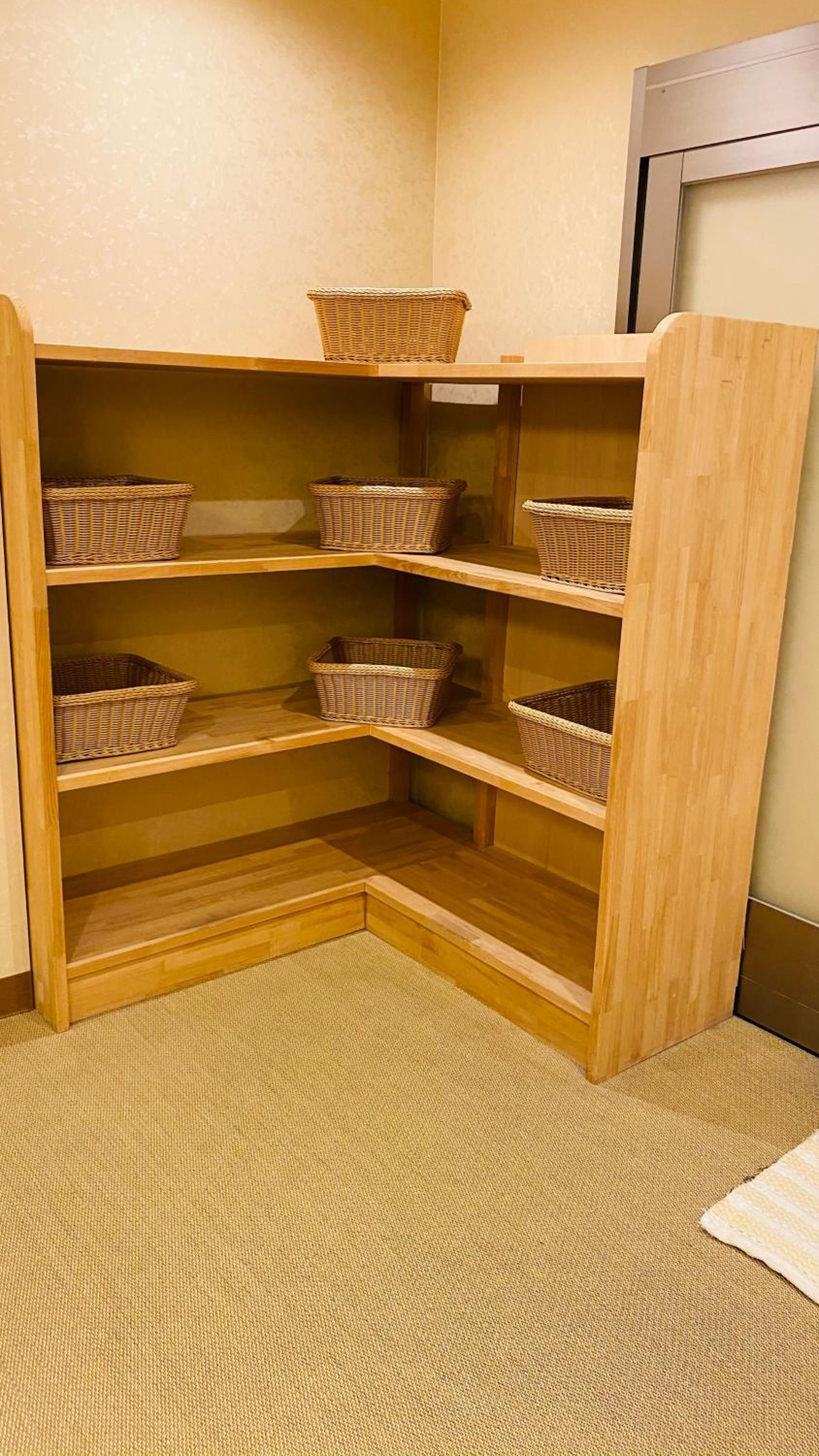 A corner storage unit with multiple wicker baskets on shelves.