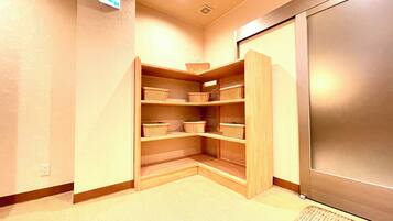 A corner storage unit with multiple shelves and baskets, a power outlet, and a door leading to another room.