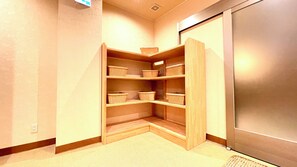 A corner storage unit with multiple shelves and baskets, a power outlet, and a door leading to another room.