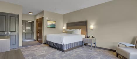 A hotel room with a large bed, a desk, a chair, and a small table.