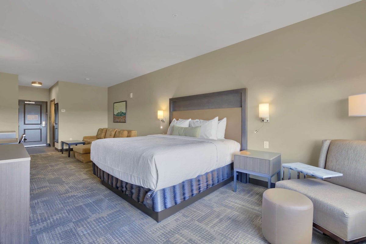 Ein Hotelzimmer mit einem großen Bett, einer Couch, einem kleinen Tisch und einem Sessel.