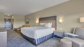 A hotel room with a large bed, a sofa, a small table, and a chair.