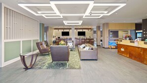 A modern hotel lobby with a reception desk, seating area, and a bar. - Best Western Plus Fillmore Inn & Suites (Colorado Springs)