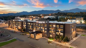 A multi-story hotel with a central courtyard, a parking lot, and a mountainous backdrop. - Best Western Plus Fillmore Inn & Suites (Colorado Springs)