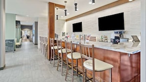 A modern bar area with a long counter, multiple bar stools, and overhead lighting. - Best Western Plus Fillmore Inn & Suites (Colorado Springs)