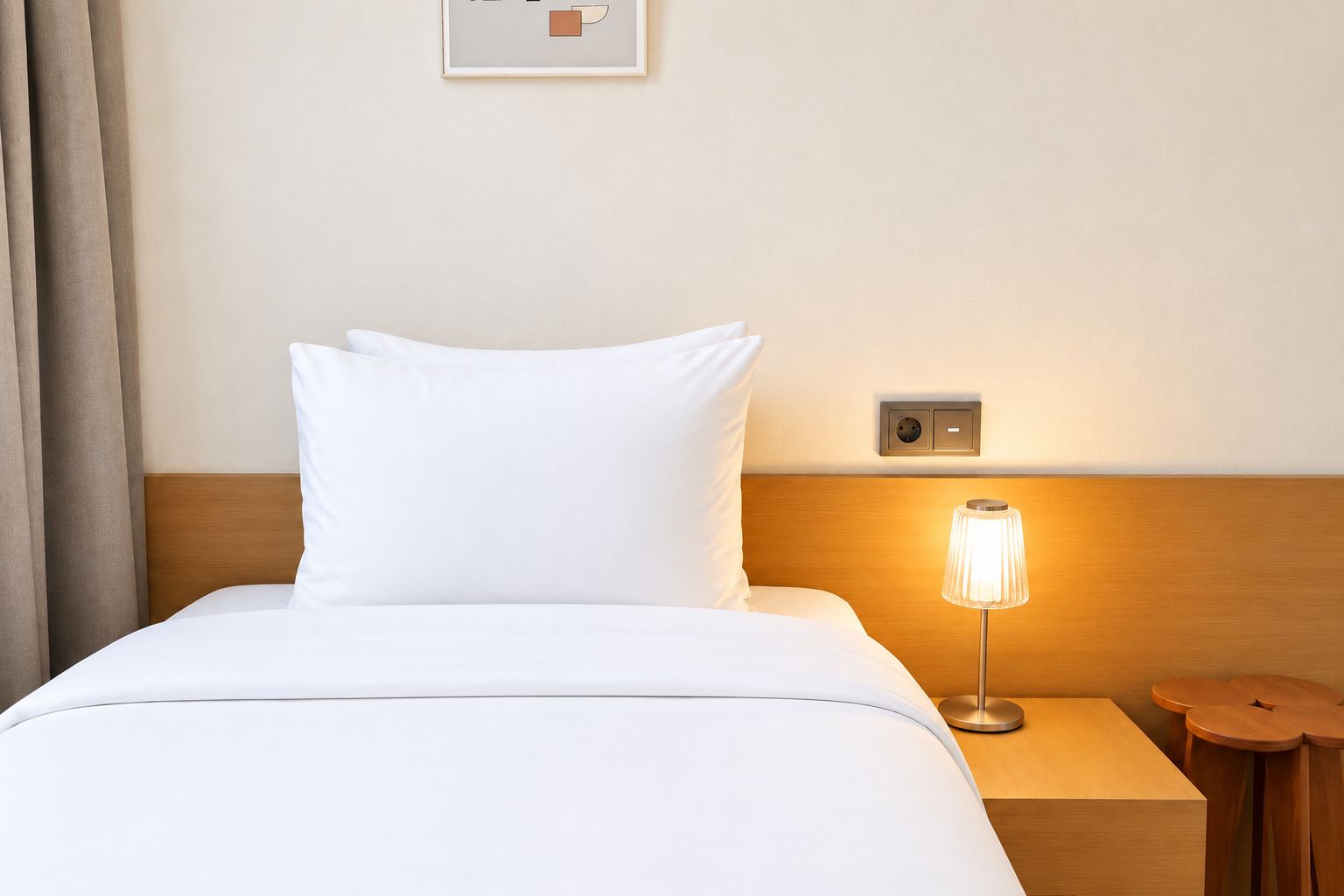Habitación de hotel con cama, mesita de noche con lámpara y enchufe en la pared.