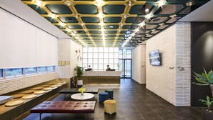 A modern lobby with a reception desk, seating areas, and a unique ceiling design. - Hotel Newv (Seoul)