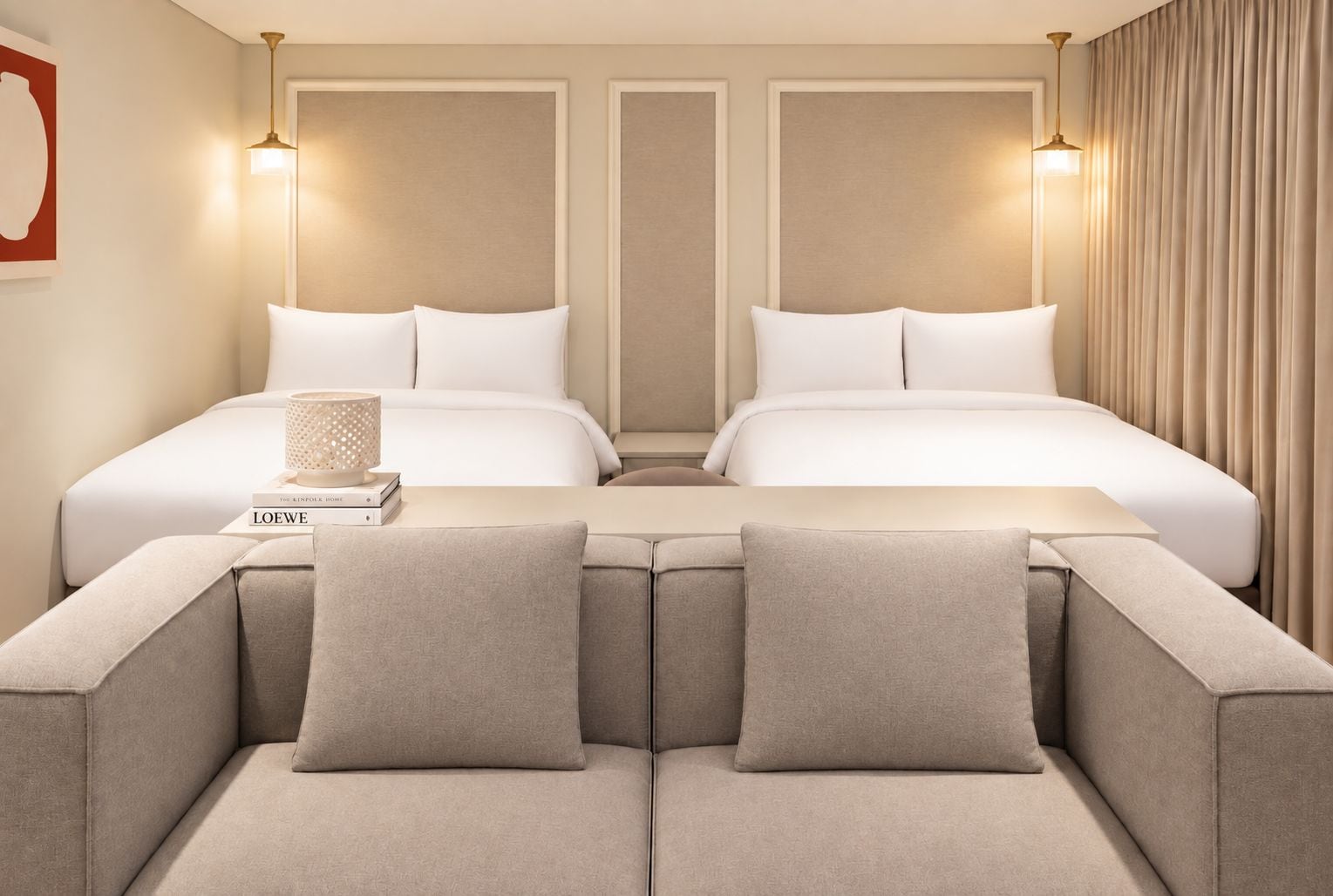 A hotel room with two beds, a sofa, and a lamp.