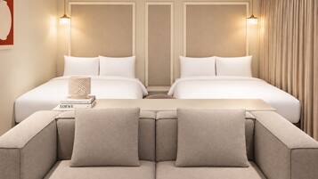 A hotel room with two beds, a sofa, and a lamp.