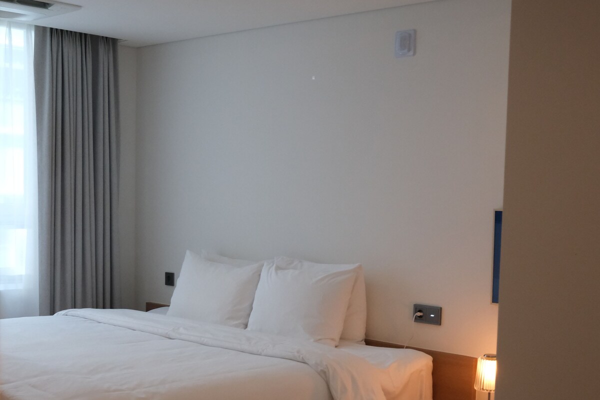 Une chambre d’hôtel moderne avec un grand lit, une table de chevet et une lampe.