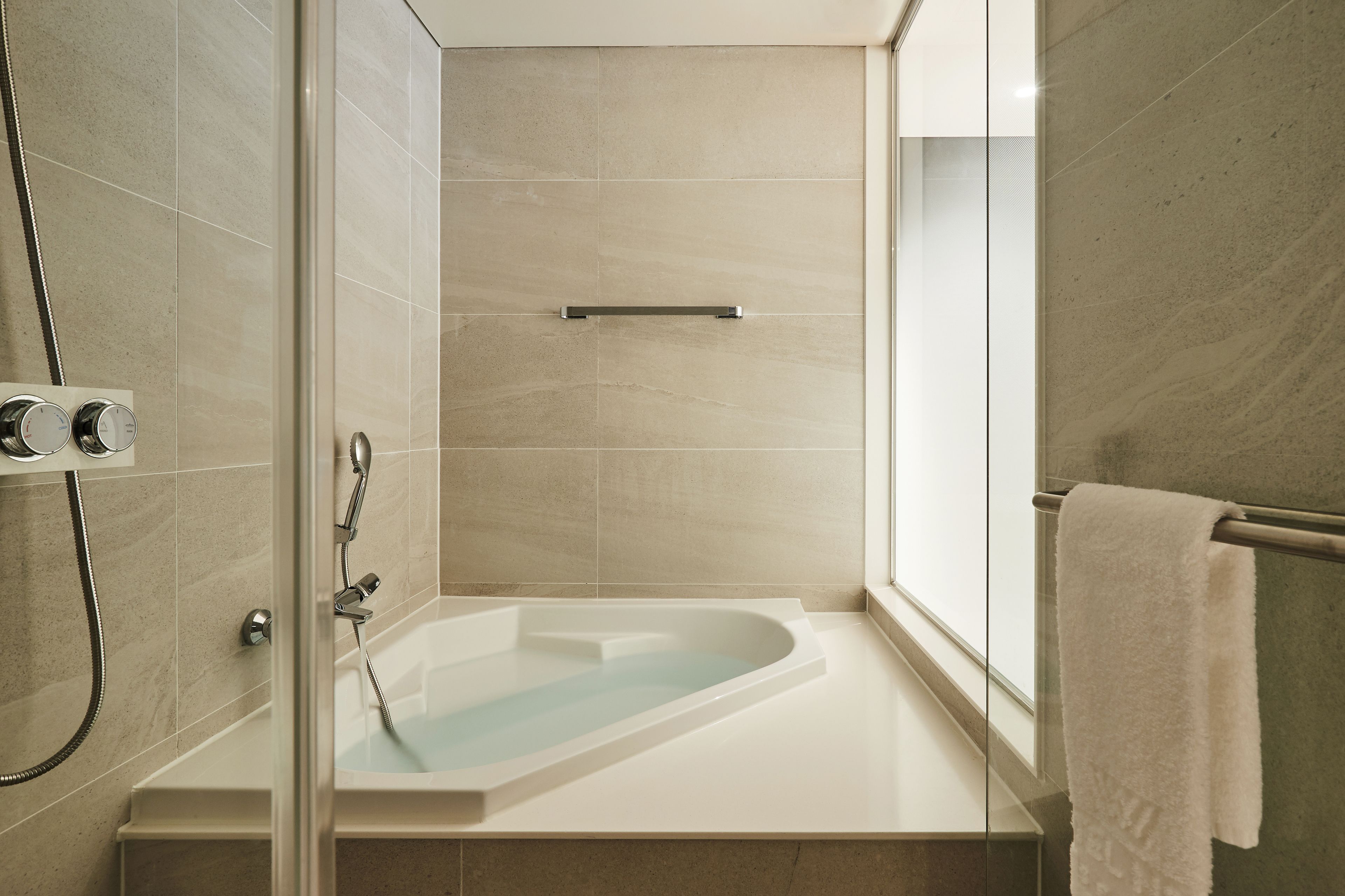 A modern bathroom with a freestanding bathtub, a glass shower enclosure, and a towel rack.