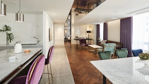 A modern hotel room with a kitchen area, dining space, and a seating area with a view of the city. - Hotel Newv (Seoul)