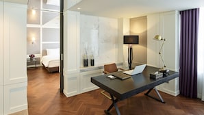 A modern hotel room with a large desk, a bed, a seating area, and a view of the city. - Hotel Newv (Seoul)