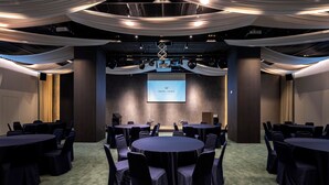 A conference room with round tables and chairs, a projector screen, and draped fabric on the ceiling. - Hotel Newv (Seoul)