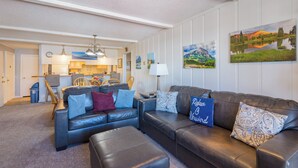 A modern living room with a leather sofa, a dining area, and a kitchen in the background. - Ski-In/Out! 3/2 Slopeside Spacious Condo w/ Amazing Mtn Views!! (Mt. Crested Butte)