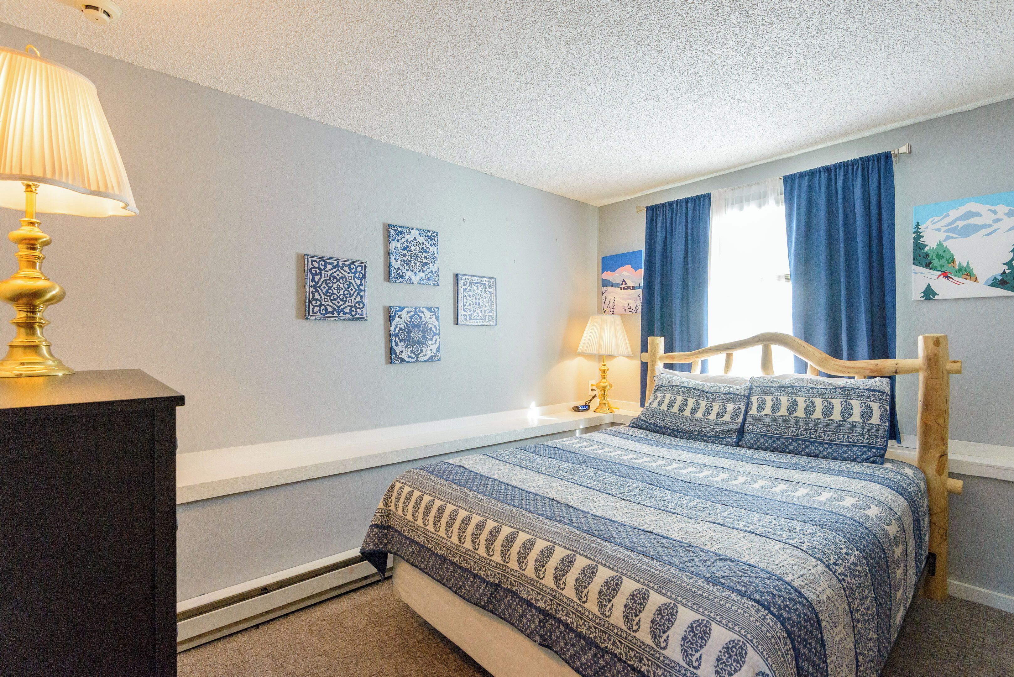 Un dormitorio con cama, mesita de noche, lámpara y decoración en la pared.