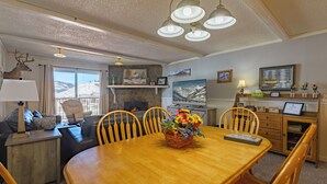 A cozy living room with a fireplace, a dining table with chairs, a sofa, and a television. - Ski-In/Out! 3/2 Slopeside Spacious Condo w/ Amazing Mtn Views!! (Mt. Crested Butte)