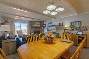 A cozy living room with a fireplace, a dining table with chairs, a sofa, and a television.