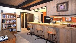 A bar area with a wooden counter, bar stools, and a bookshelf filled with books. - Location is Everything! Ski-In/Out Condo, No Stairs, End Unit + VIEWS (Mt. Crested Butte)