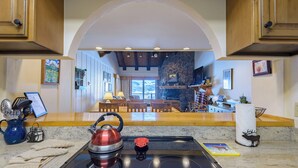 Una cocina con chimenea de piedra, armarios de madera y vistas al área de estar.