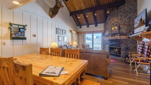 Un ambiente acogedor con una mesa de comedor de madera, una chimenea y una pared de piedra.