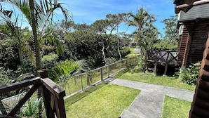 A wooden deck with a metal railing overlooking a well-maintained garden with various trees and a pathway. - Tokashiki Guest House (Tokashiki)