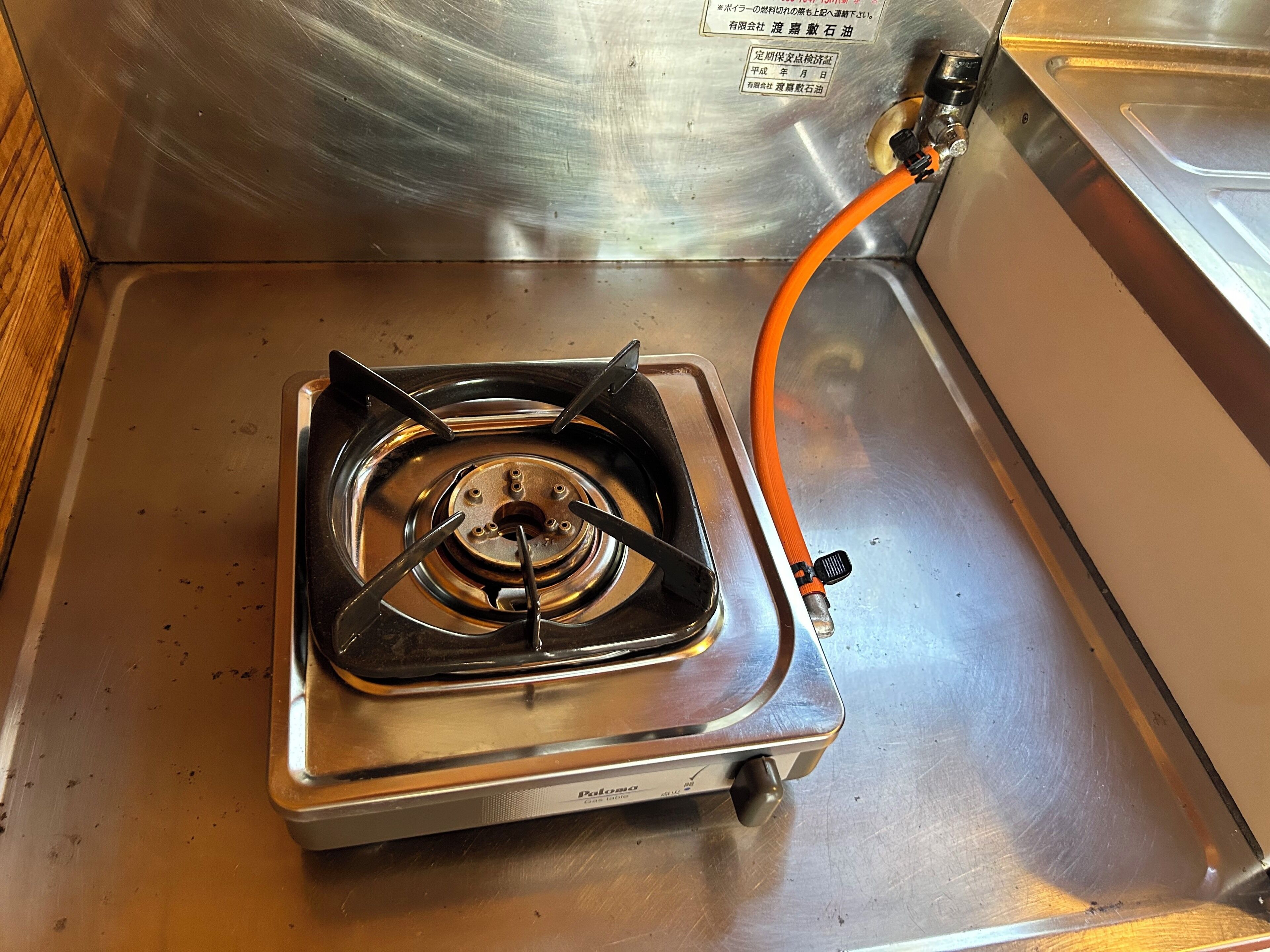 A stainless steel gas stove with a visible gas pipe connection.