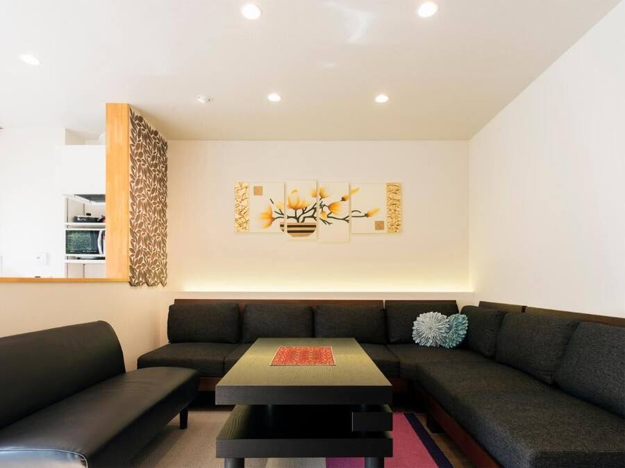 Una sala de estar moderna con un sofá seccional, una mesa de centro y una obra de arte colgada en la pared.