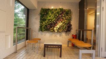 A modern indoor seating area with a green wall, a tiled floor, and a glass door leading to an outdoor balcony.