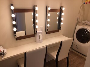 Un meuble-lavabo de salle de bain avec deux miroirs, un sèche-cheveux et un lave-linge.