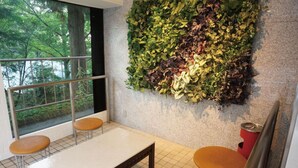 Ein modernes Zimmer mit großem Fenster, einem weißen Tisch, zwei Holzstühlen und einer grünen Wandgestaltung.