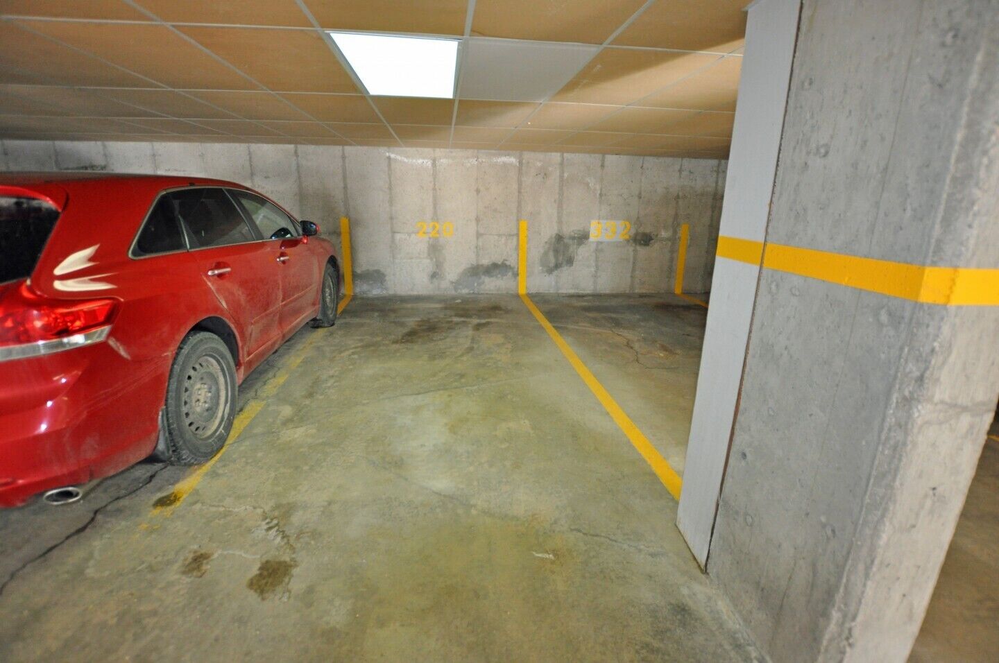 A parking garage with concrete walls and yellow lines marking parking spaces.